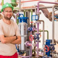 industry-worker-posing-inside-factory-with-bars-pipes-around